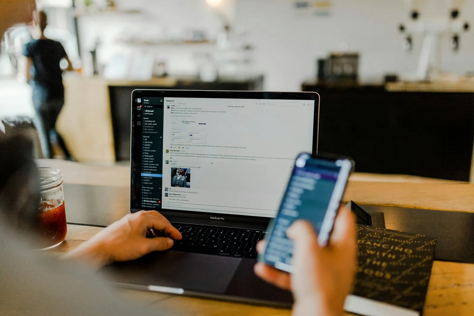 Person using a laptop and a phone at a café table